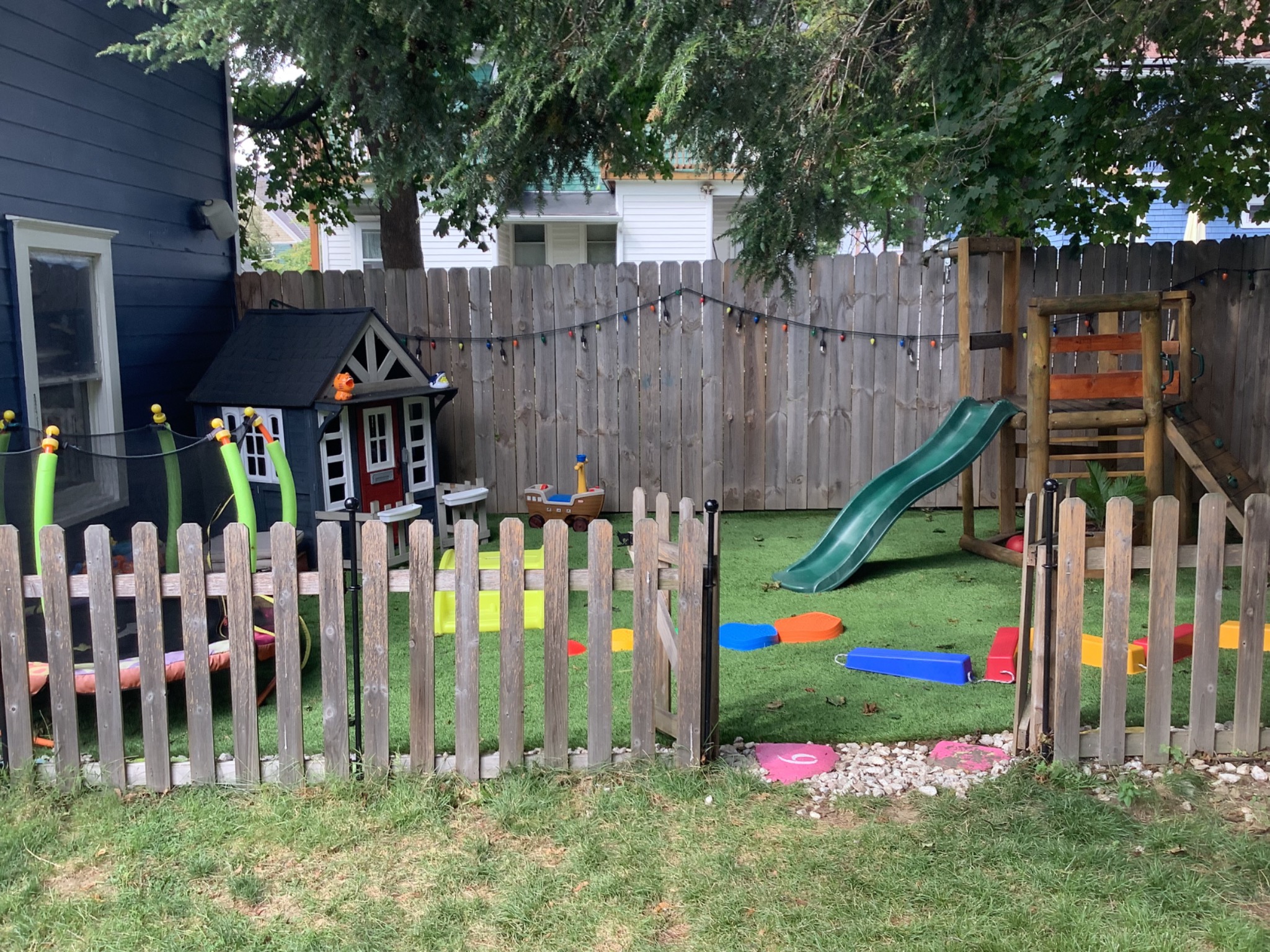 Fenced private playground with playhouse and slide