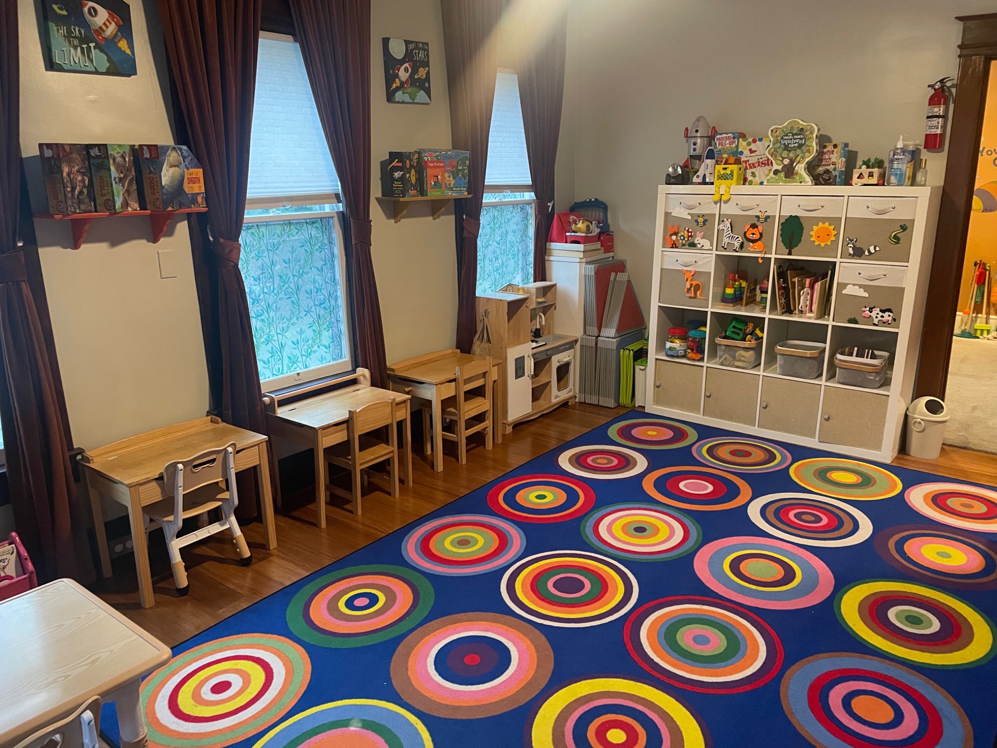 Another view of the toddler room with play shelves and a colorful circle rug